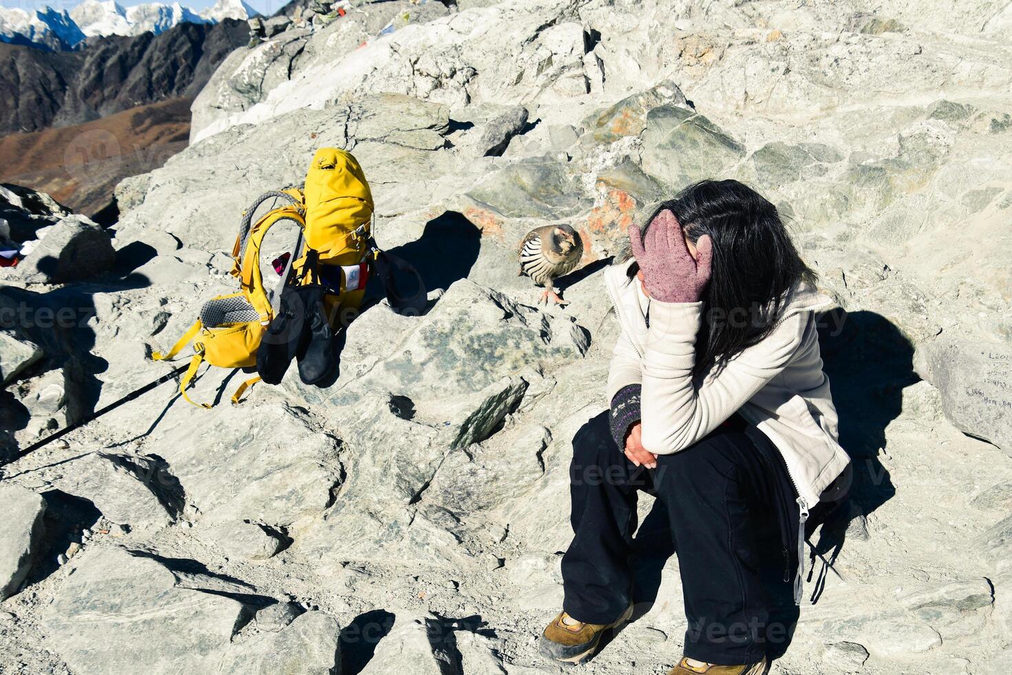 Young caucasian woman trekker resting on Chola pass in Himalayas high altitude feeling low oxygen level affects of dizziness and weakness photo