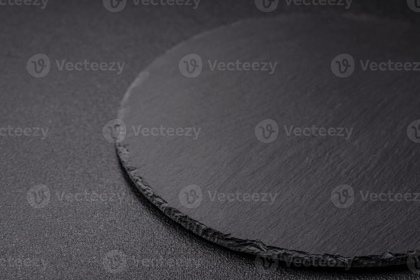 Empty round slate plate for template on the black background photo