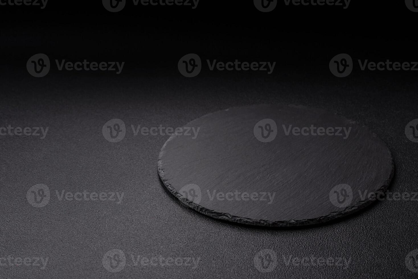 Empty round slate plate for template on the black background photo