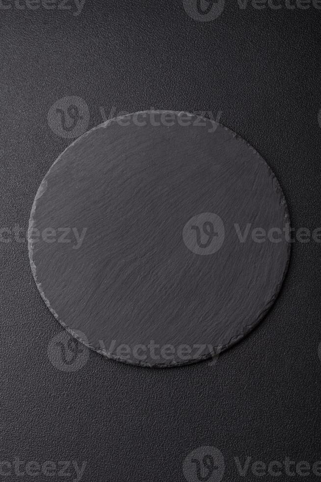 Empty round slate plate for template on the black background photo