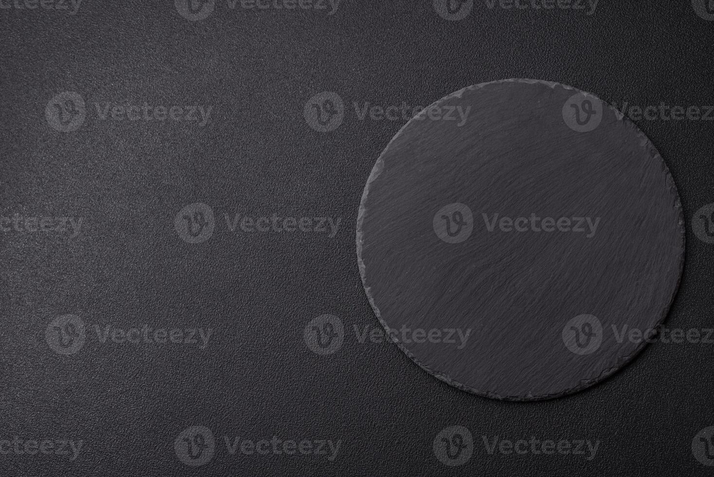 Empty round slate plate for template on the black background photo