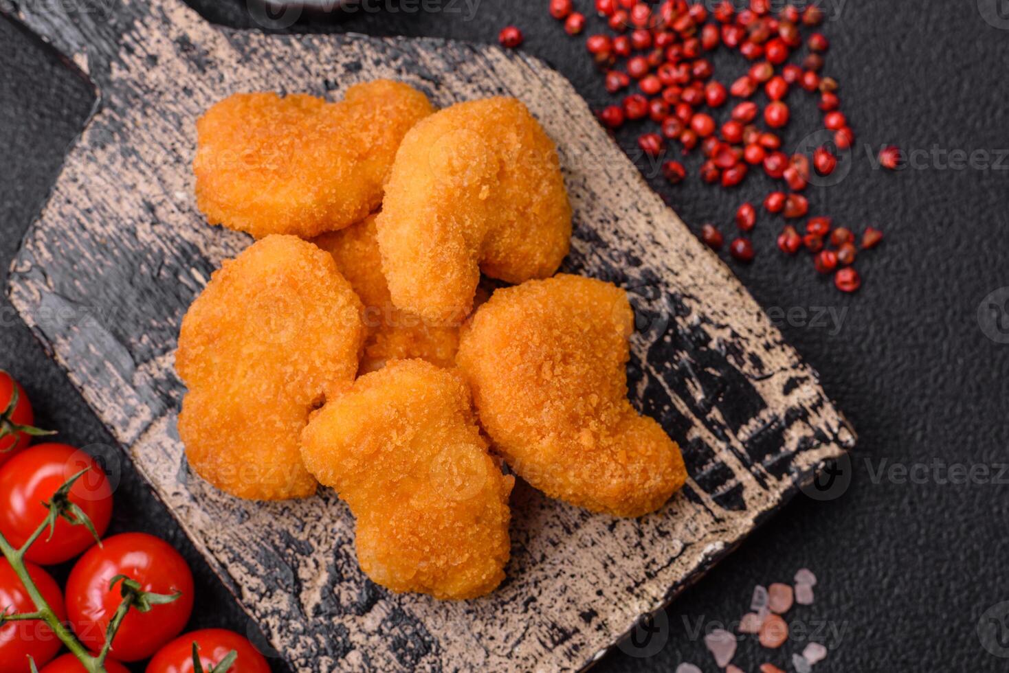 Delicious fresh crispy chicken nuggets on a dark concrete background photo