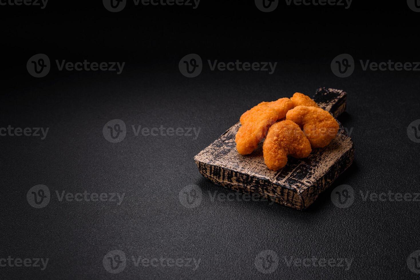 Delicious fresh crispy chicken nuggets on a dark concrete background photo