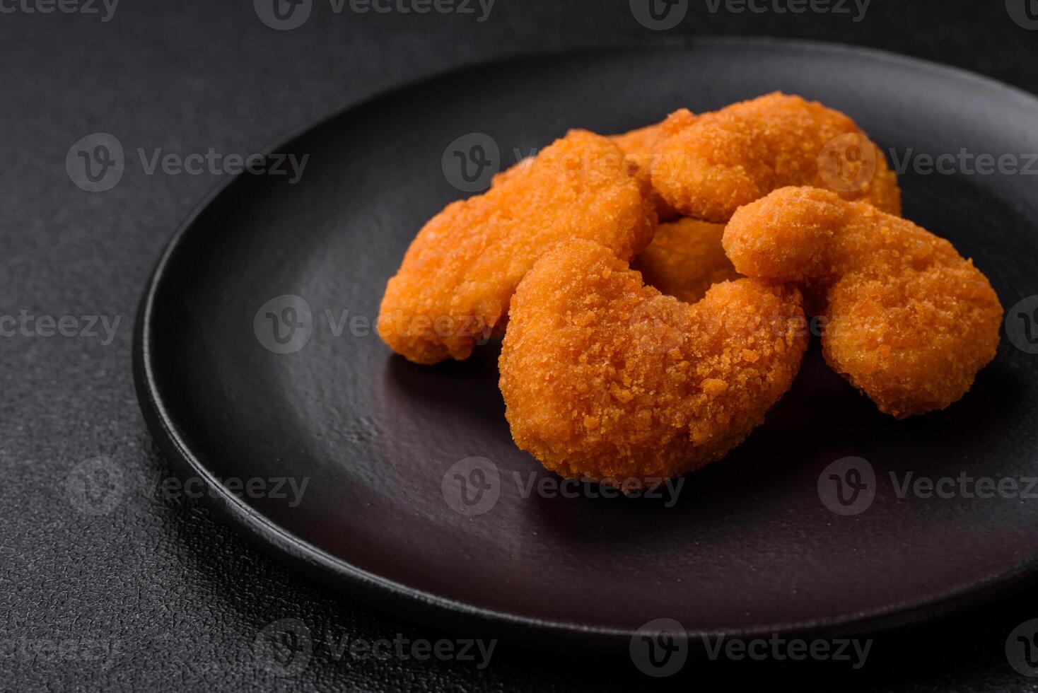 Delicious fresh crispy chicken nuggets on a dark concrete background photo