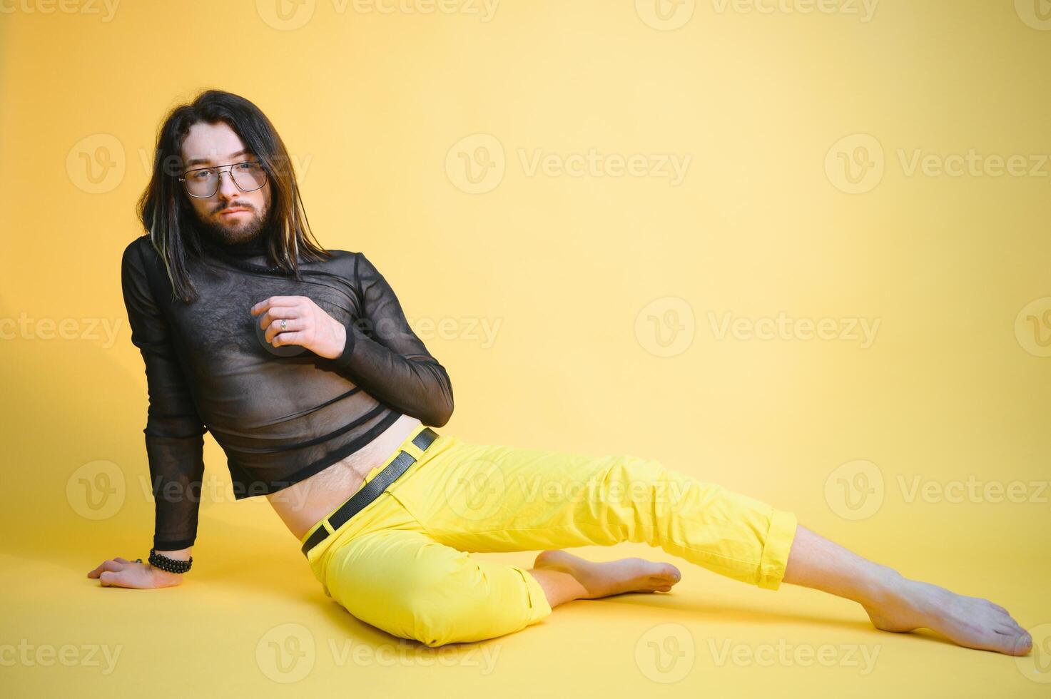 Young gay man is standing in the studio and posing for a camera. photo