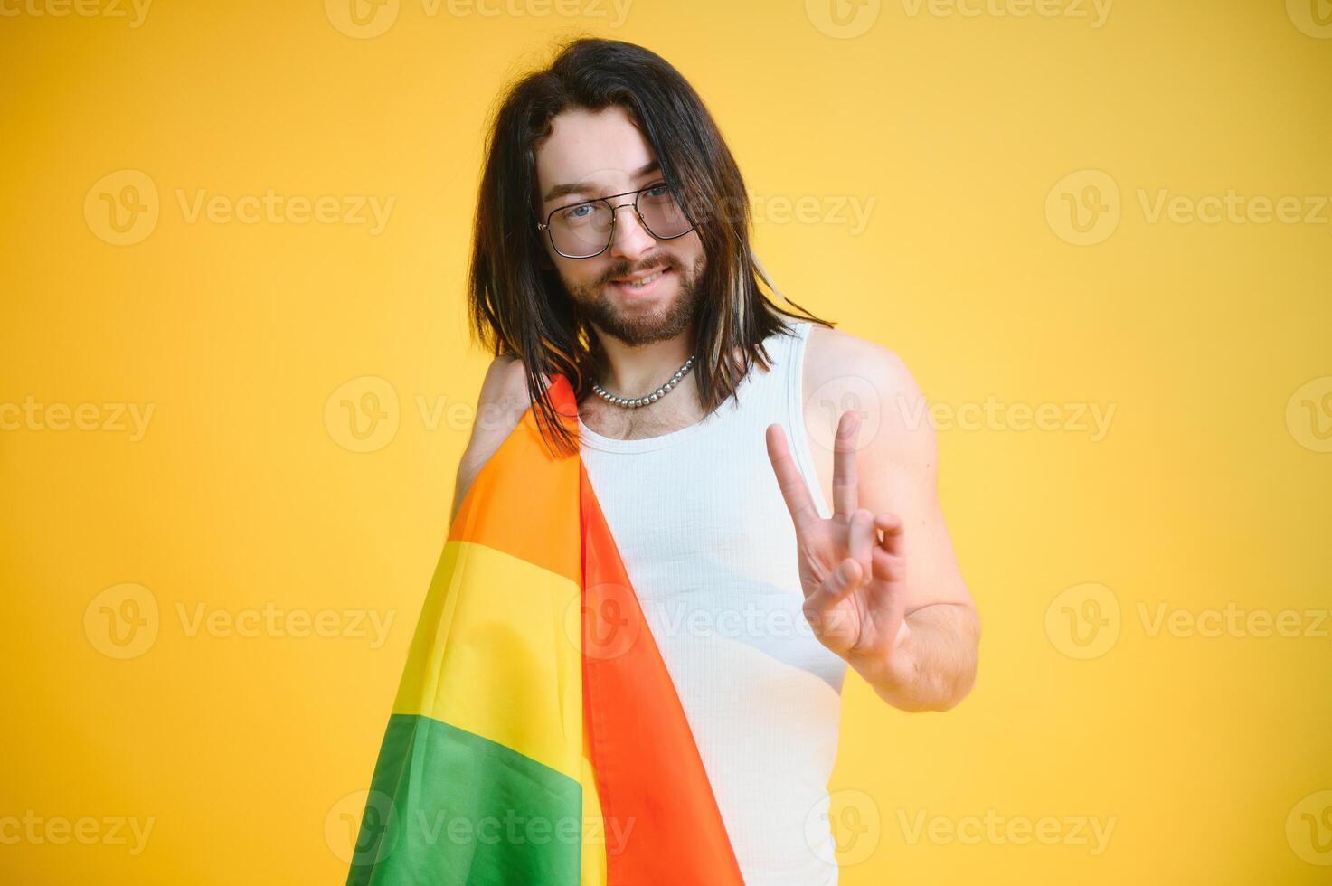 Gay man hold rainbow striped flag isolated on colored background studio portrait. People lifestyle fashion lgbtq concept photo