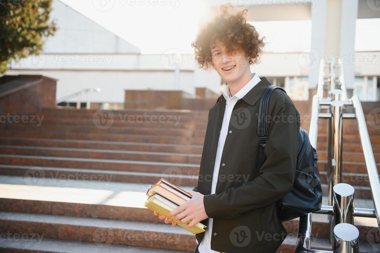 Portrait of a cheerful college student standing outside with back photo