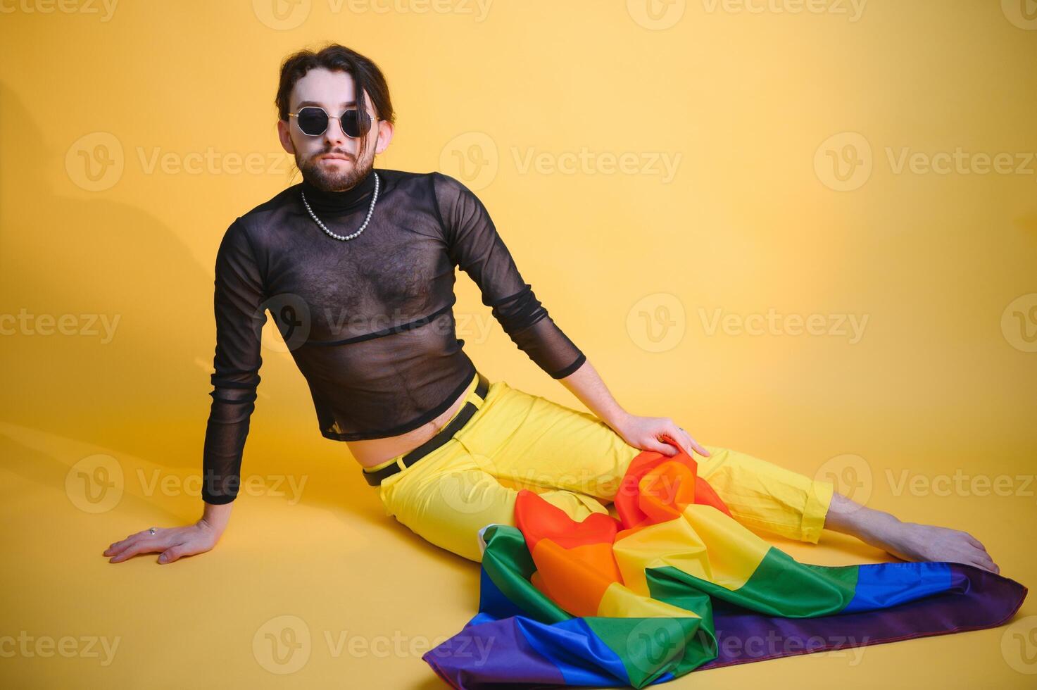 Gay man hold rainbow striped flag isolated on colored background studio portrait. People lifestyle fashion lgbtq concept photo