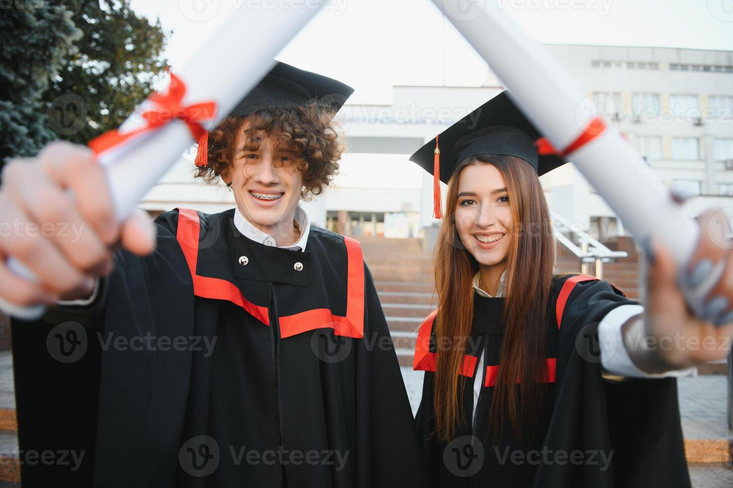 Happy friends on graduation day. Portrait of two cheerful joyful students standing near university building. photo