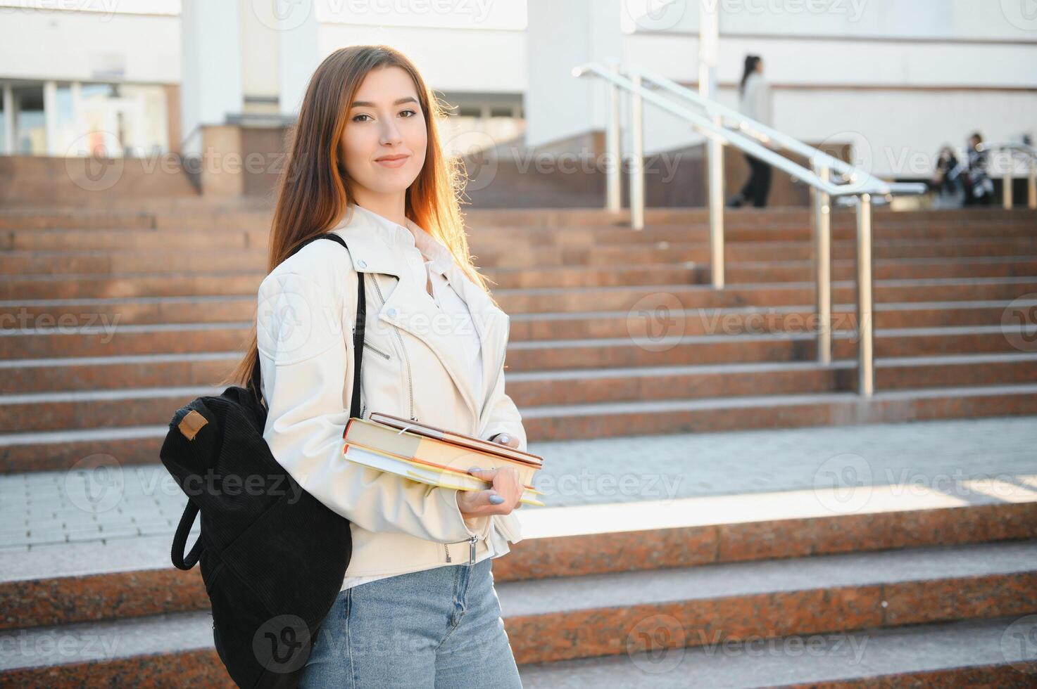 Young girl student smiling against university. Cute girl student holds folders and notebooks in hands. Learning, education concept photo