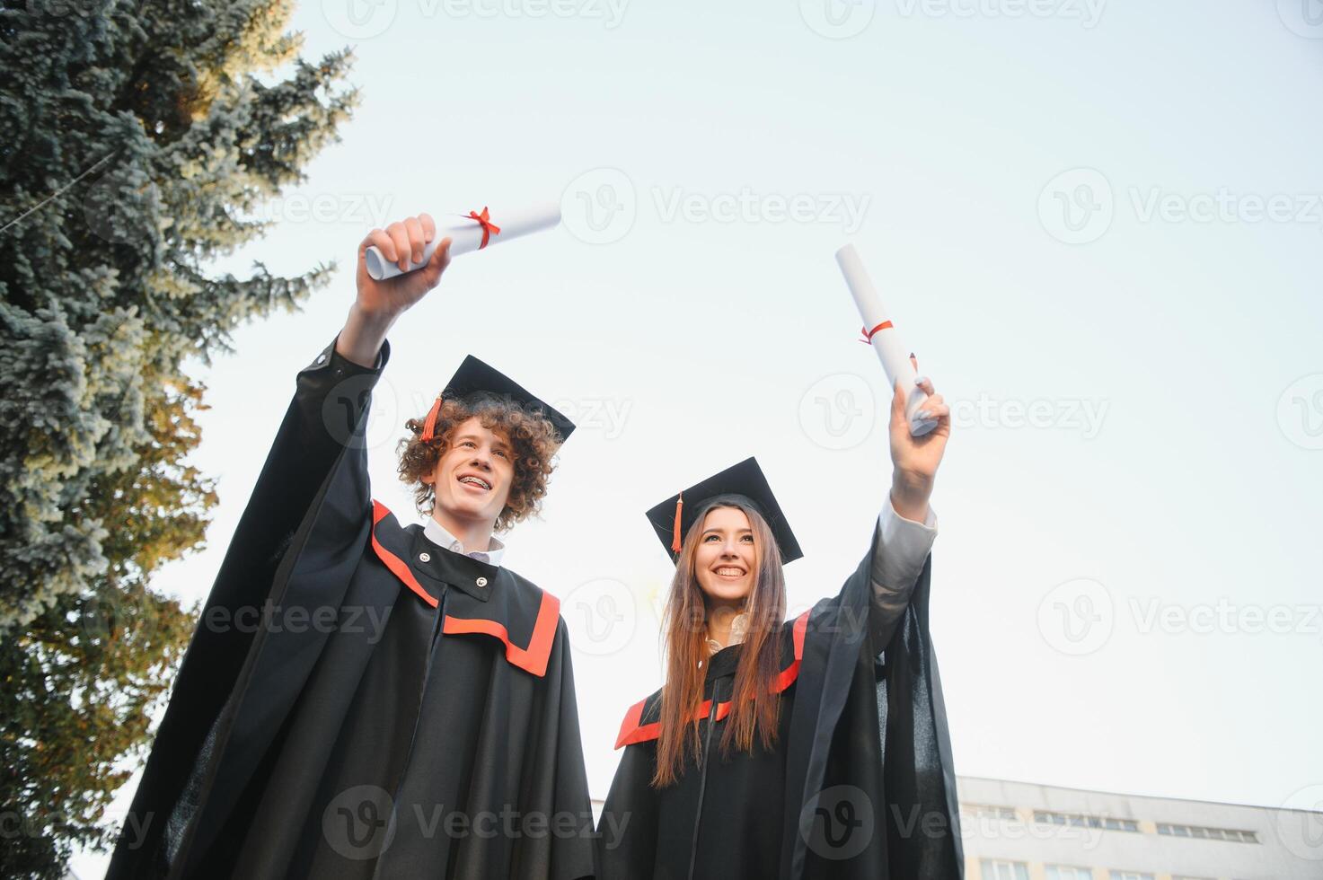 Happy friends on graduation day. Portrait of two cheerful joyful students standing near university building. photo