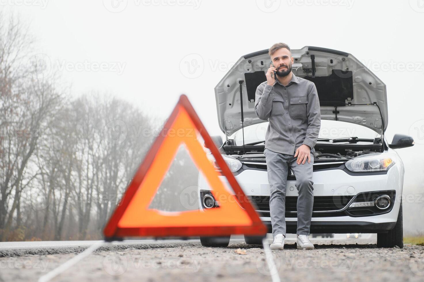 Man use a cellphone call garage in front of the open hood of a broken car on the road in the forest. Car breakdown concept. photo