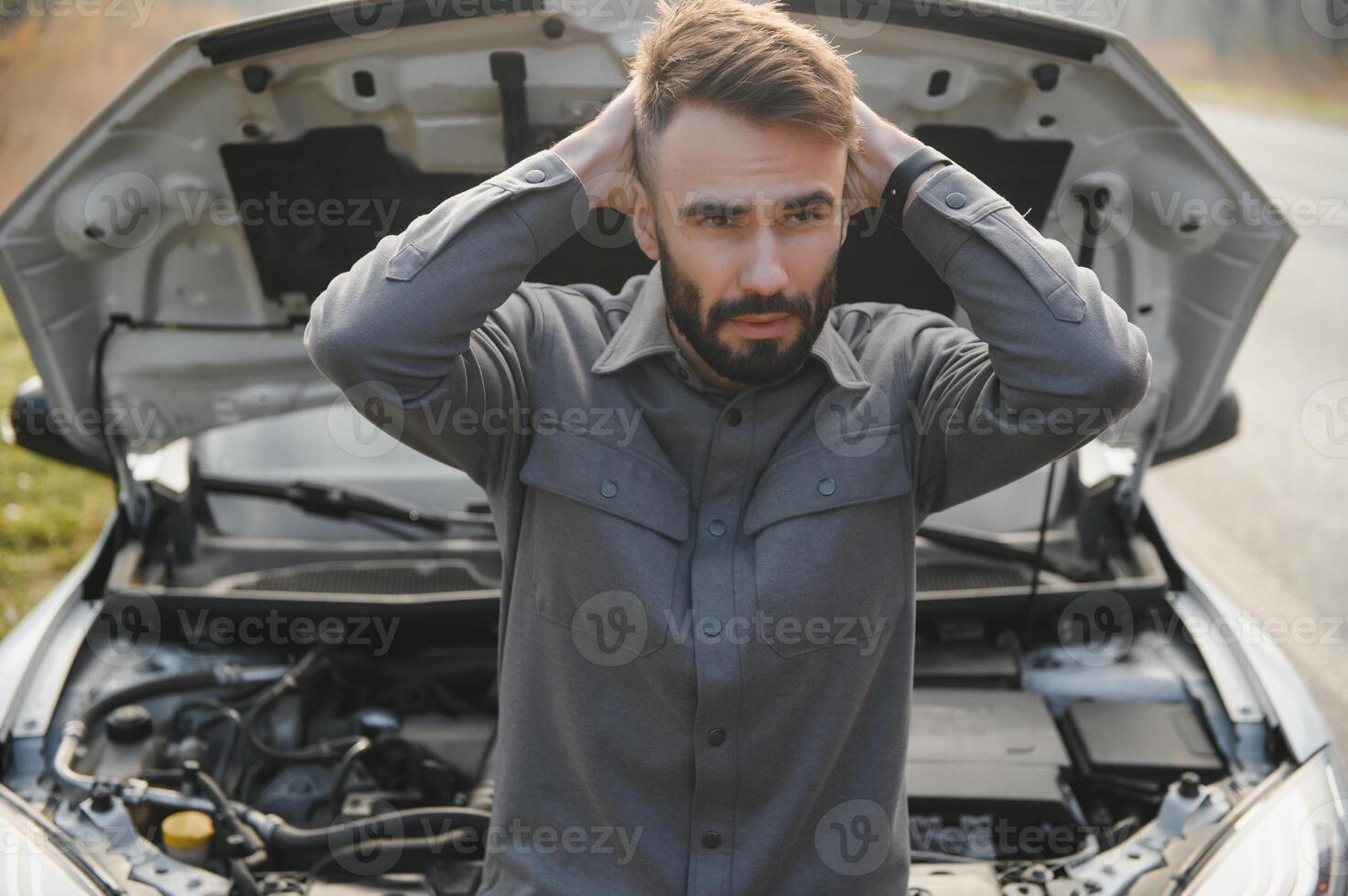 Sad driver holding his head having engine problem standing near broken car on the road. Car breakdown concept photo