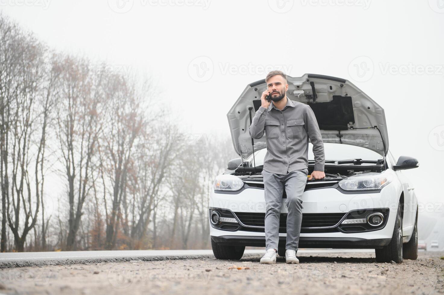 Man use a cellphone call garage in front of the open hood of a broken car on the road in the forest. Car breakdown concept. photo