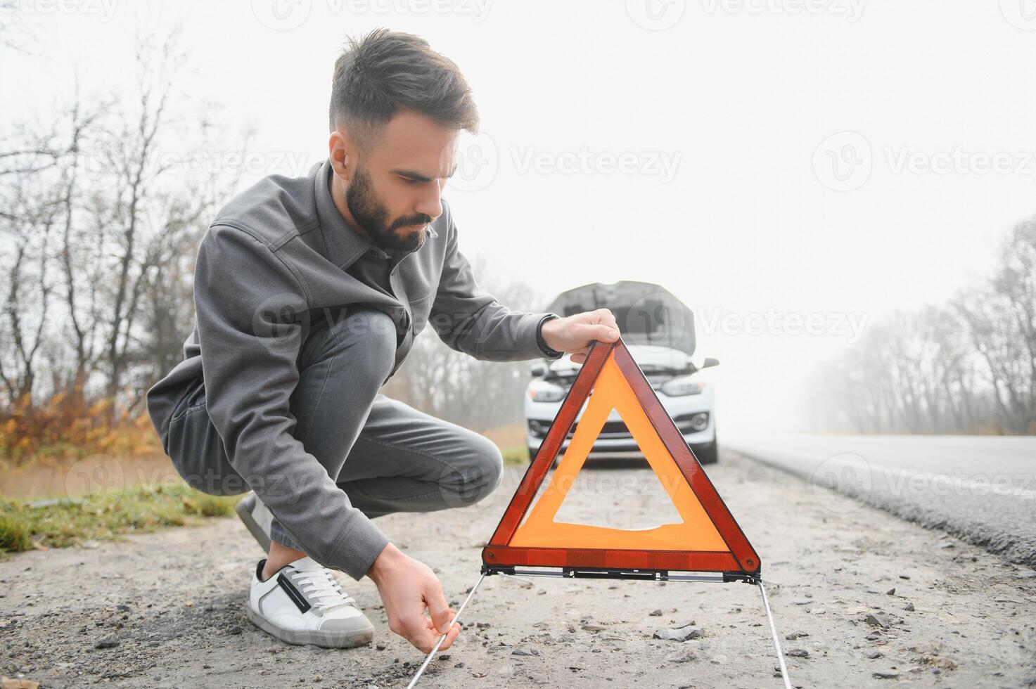 Sad man near broken car searching help in field photo