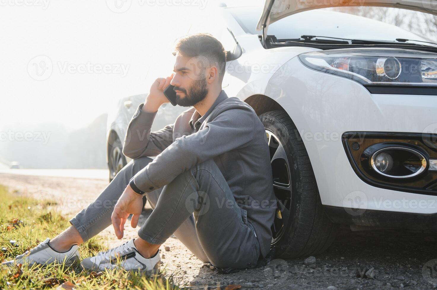 Man use a cellphone call garage in front of the open hood of a broken car on the road in the forest. Car breakdown concept. photo