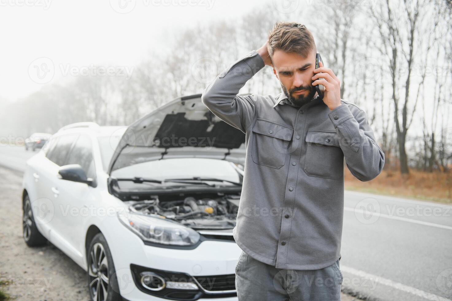 Man use a cellphone call garage in front of the open hood of a broken car on the road in the forest. Car breakdown concept. photo