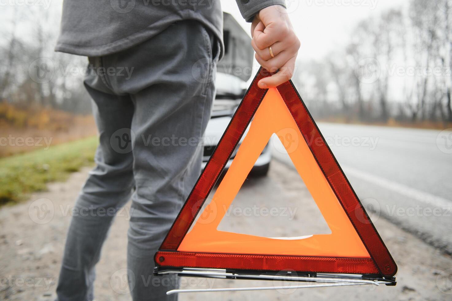 Sad driver having engine problem standing near broken car on the road. Car breakdown concept photo