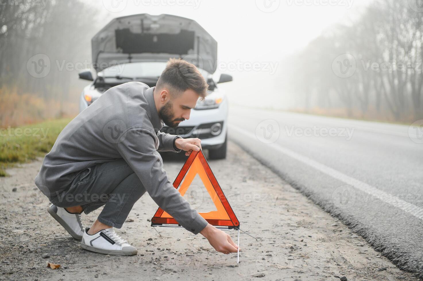 Sad driver having engine problem standing near broken car on the road. Car breakdown concept photo