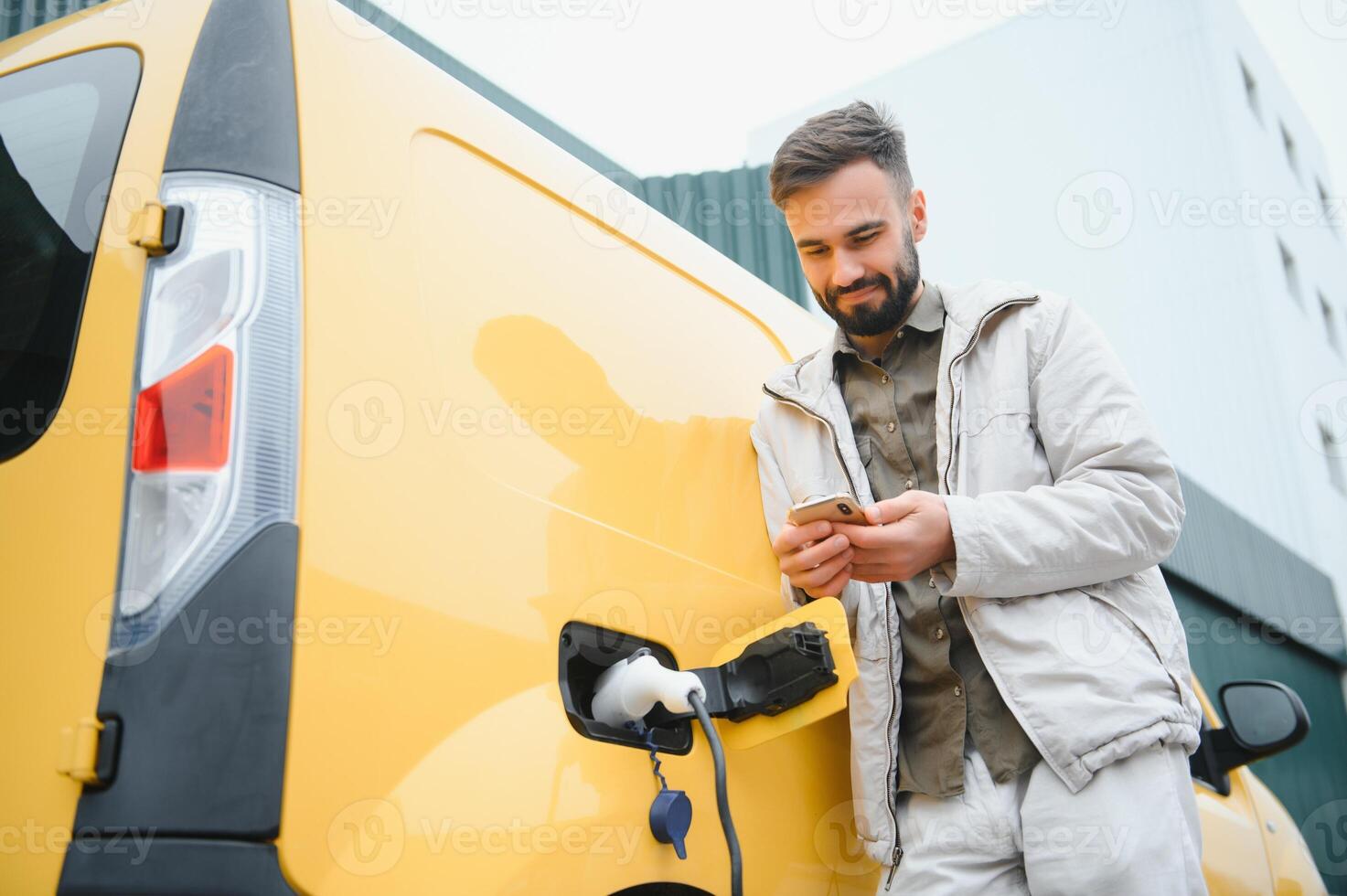 Man charging electric car by the work photo