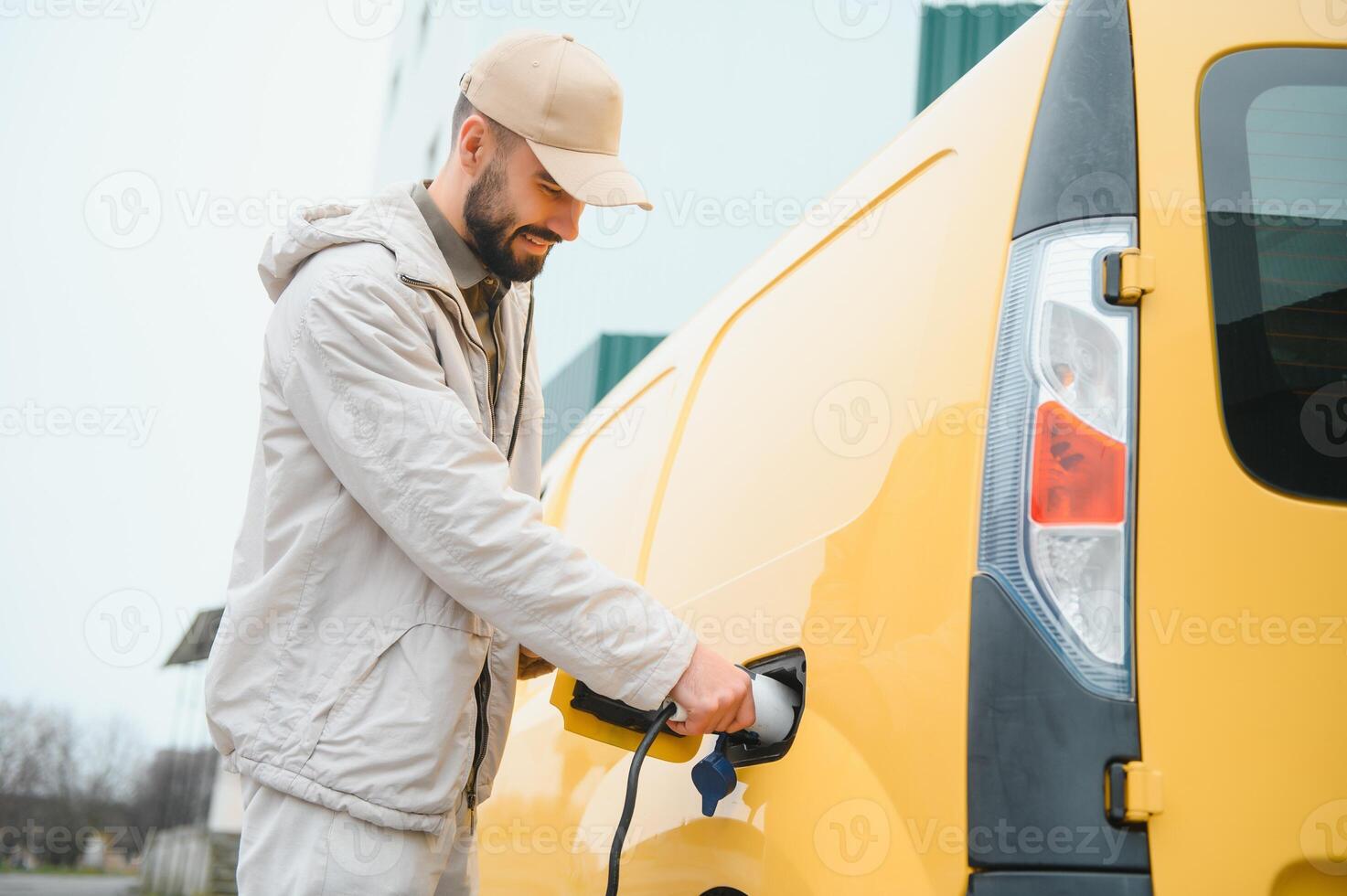 Casual man near electric car waiting for the finish of the battery charging process photo