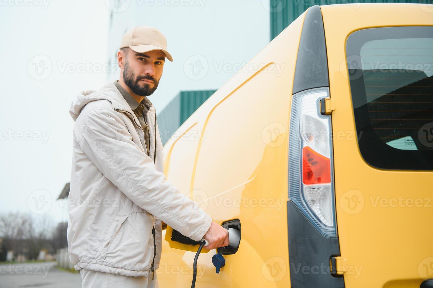 Man charging electric car by the house photo