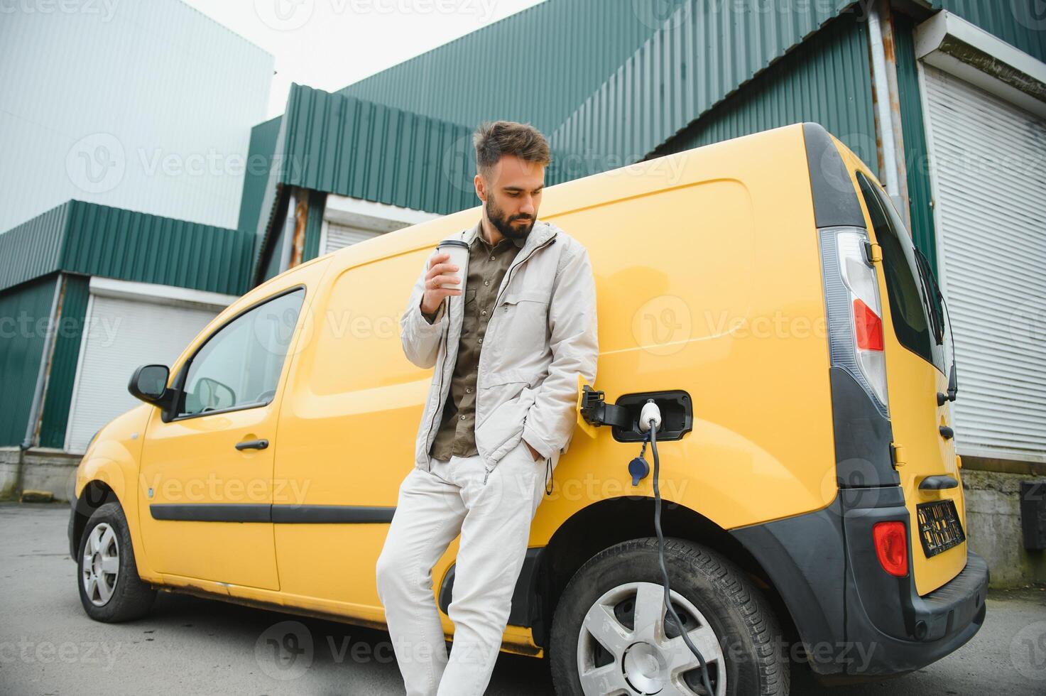Happy young adult man charging automobile battery from small public station. photo