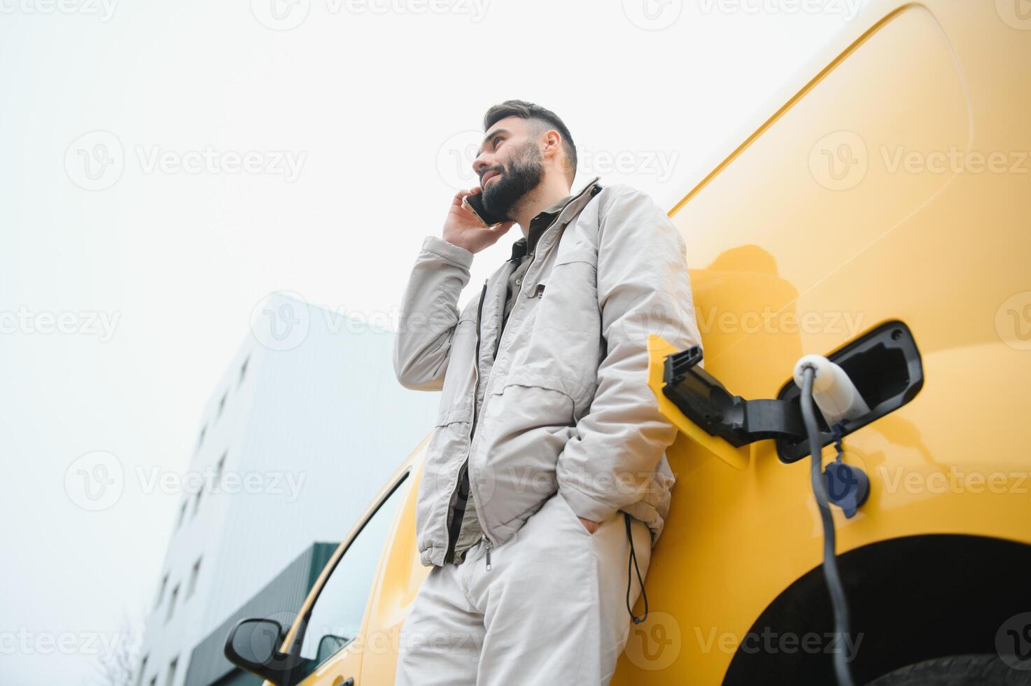 Man charging electric car by the work photo