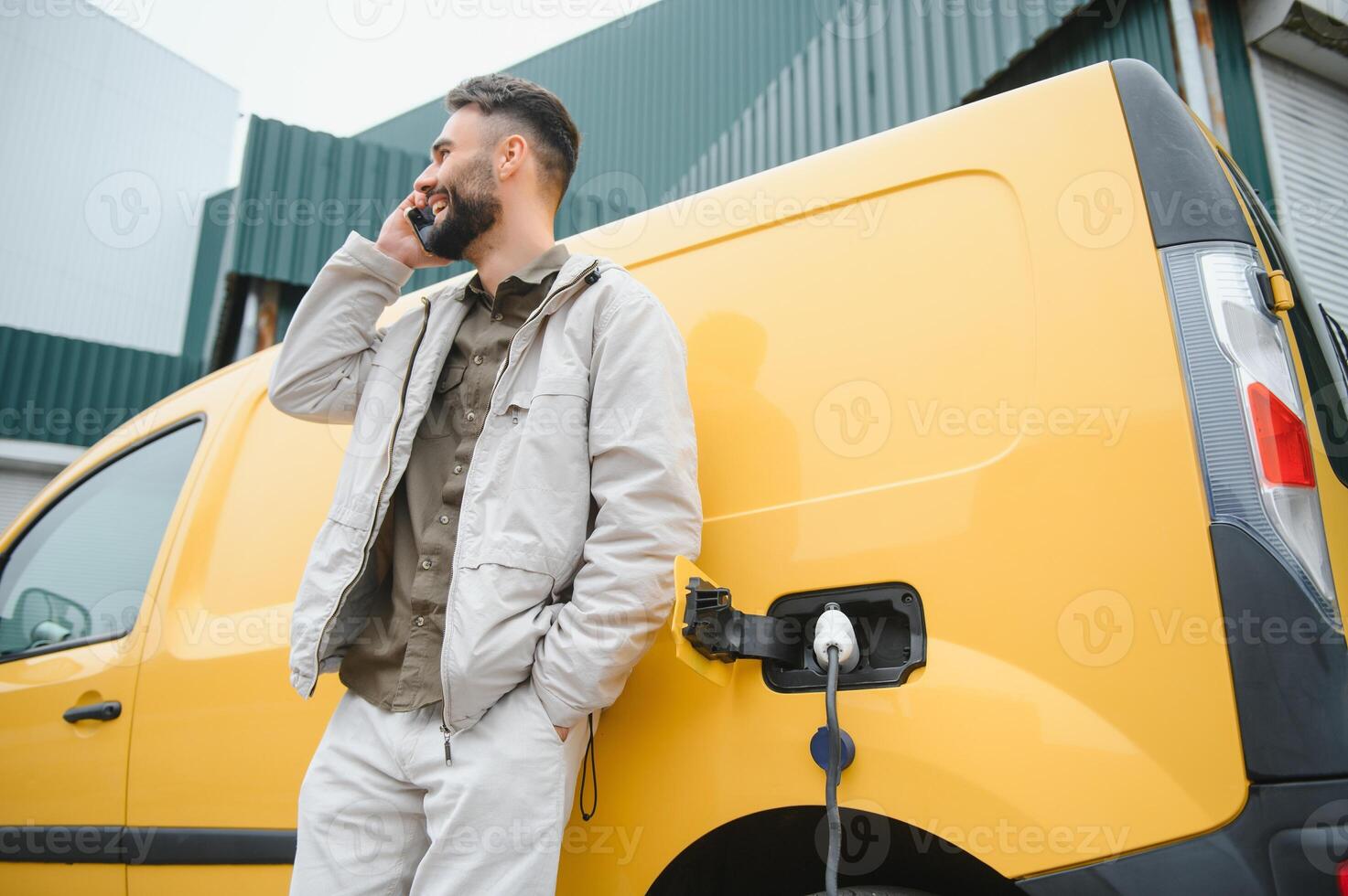 Casual man near electric car waiting for the finish of the battery charging process photo