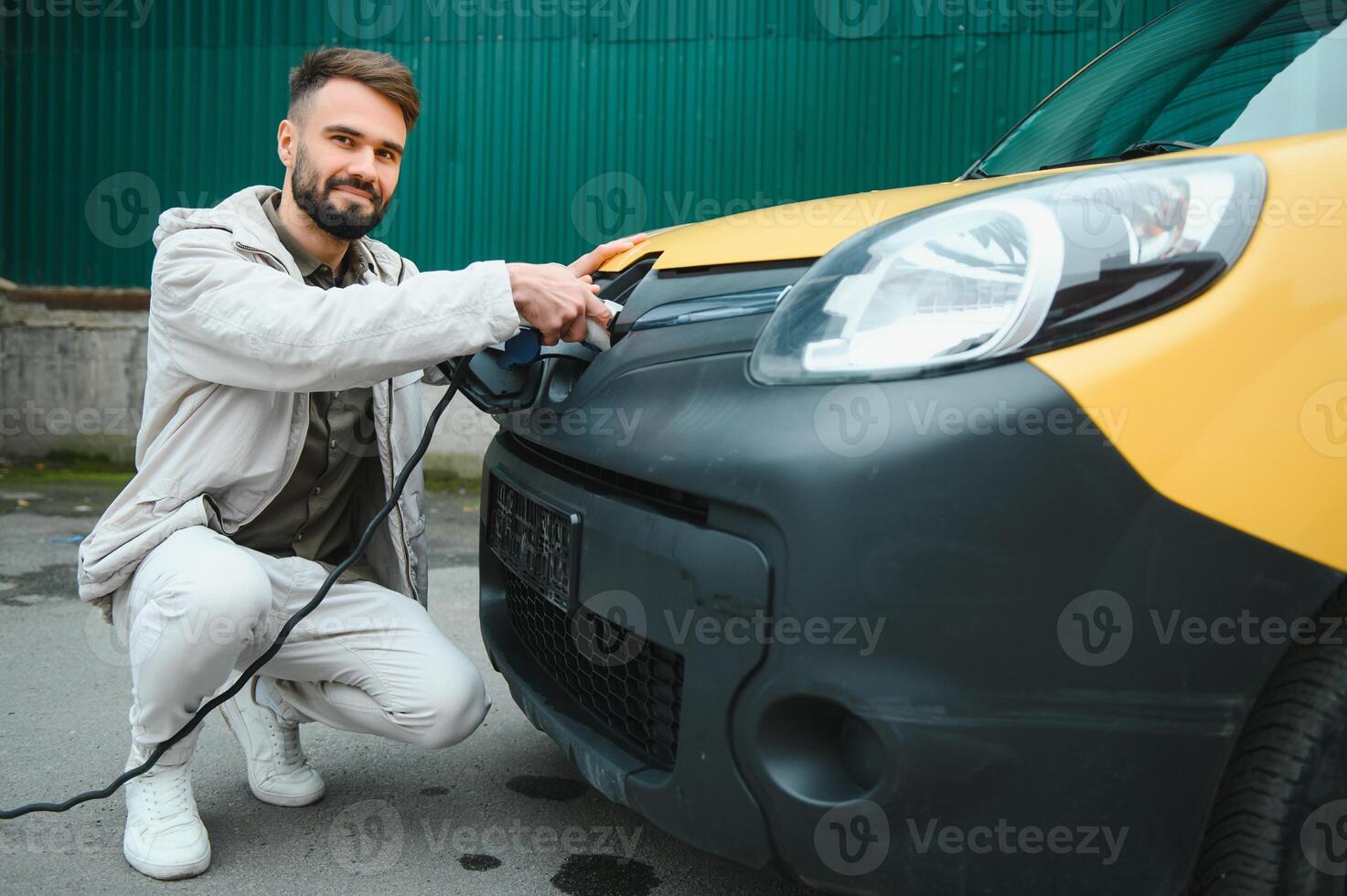 Man charging electric car by the house photo