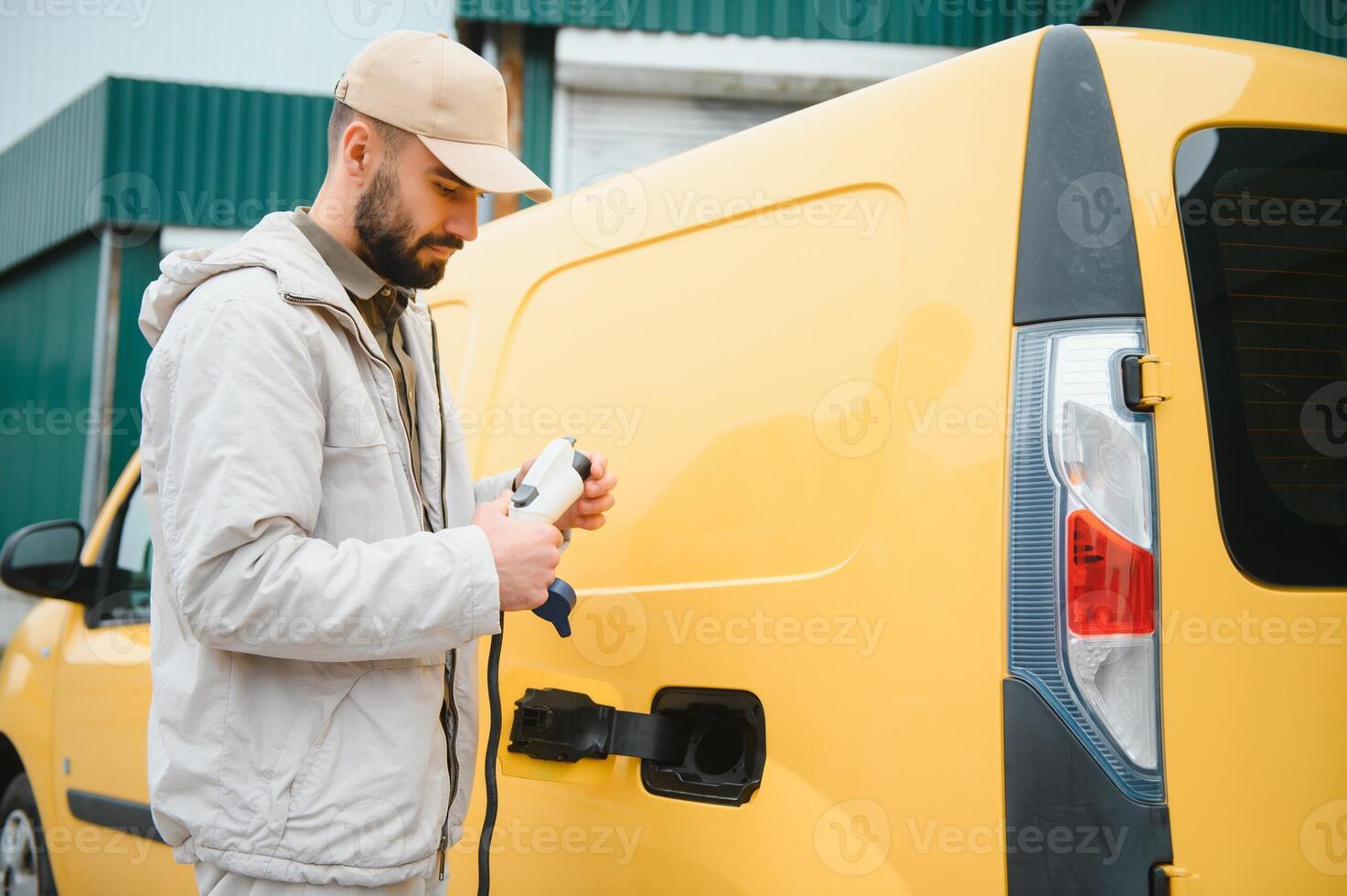 Portrait of a young man standing with charging cable near the charging station photo