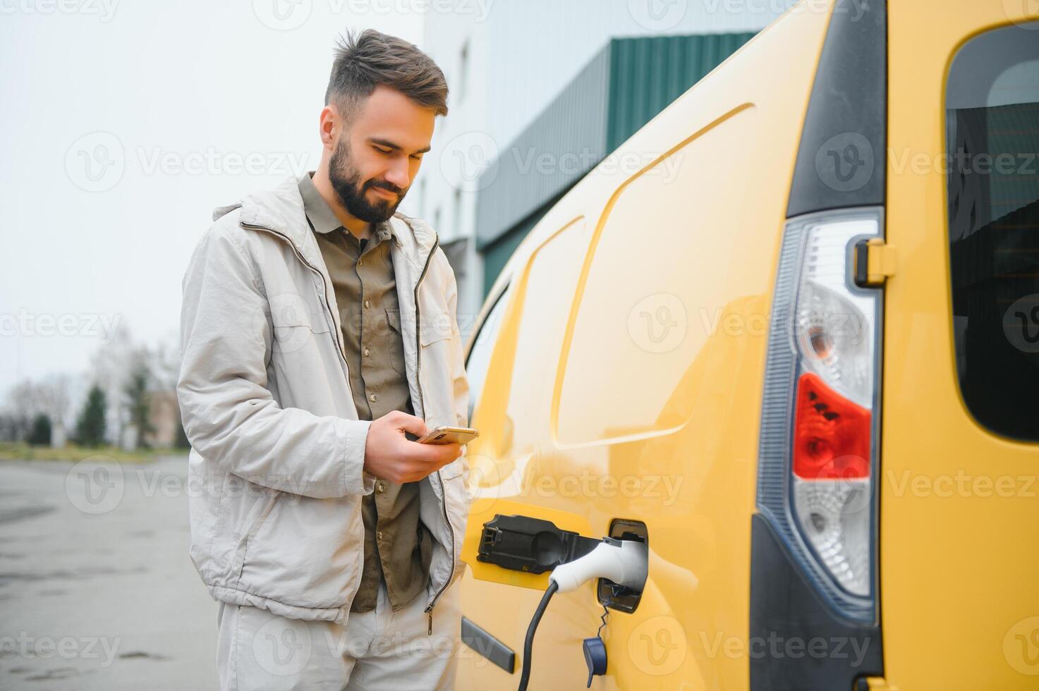 Casual man near electric car waiting for the finish of the battery charging process photo