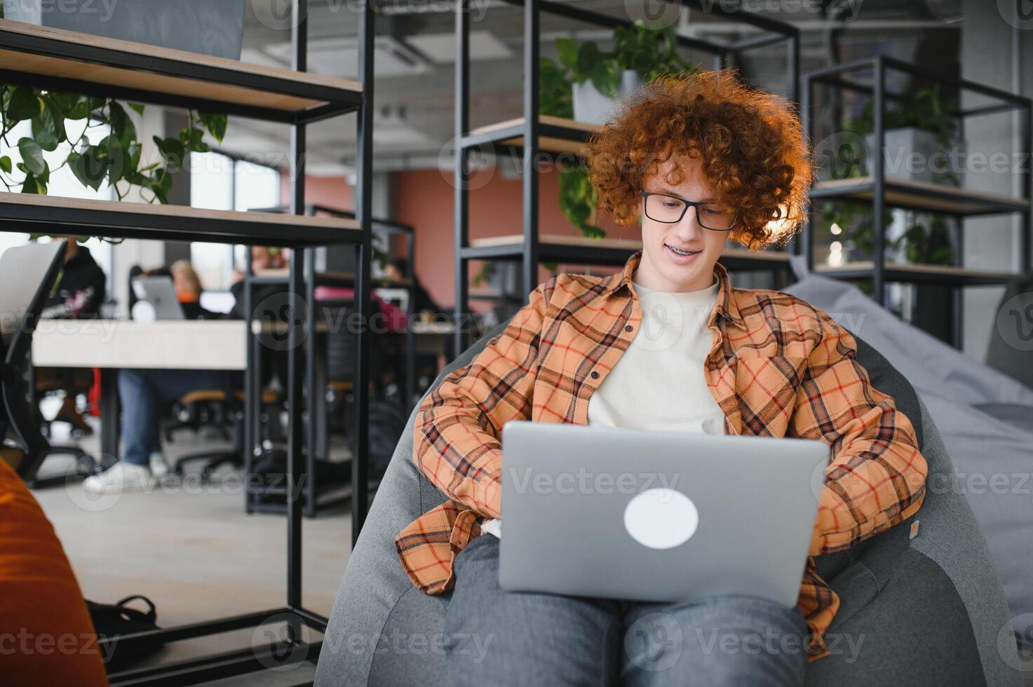 Cheerful male freelancer browsing funny content while networking in social media using netbook technology in street cafe, happy hipster guy enjoying free time for online blogging via laptop photo