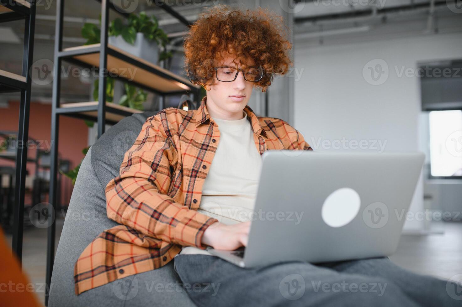 Caucasian hipster guy enjoying distance job in coffee shop, male freelancer in trendy glasses sitting in cafeteria with modern laptop device photo