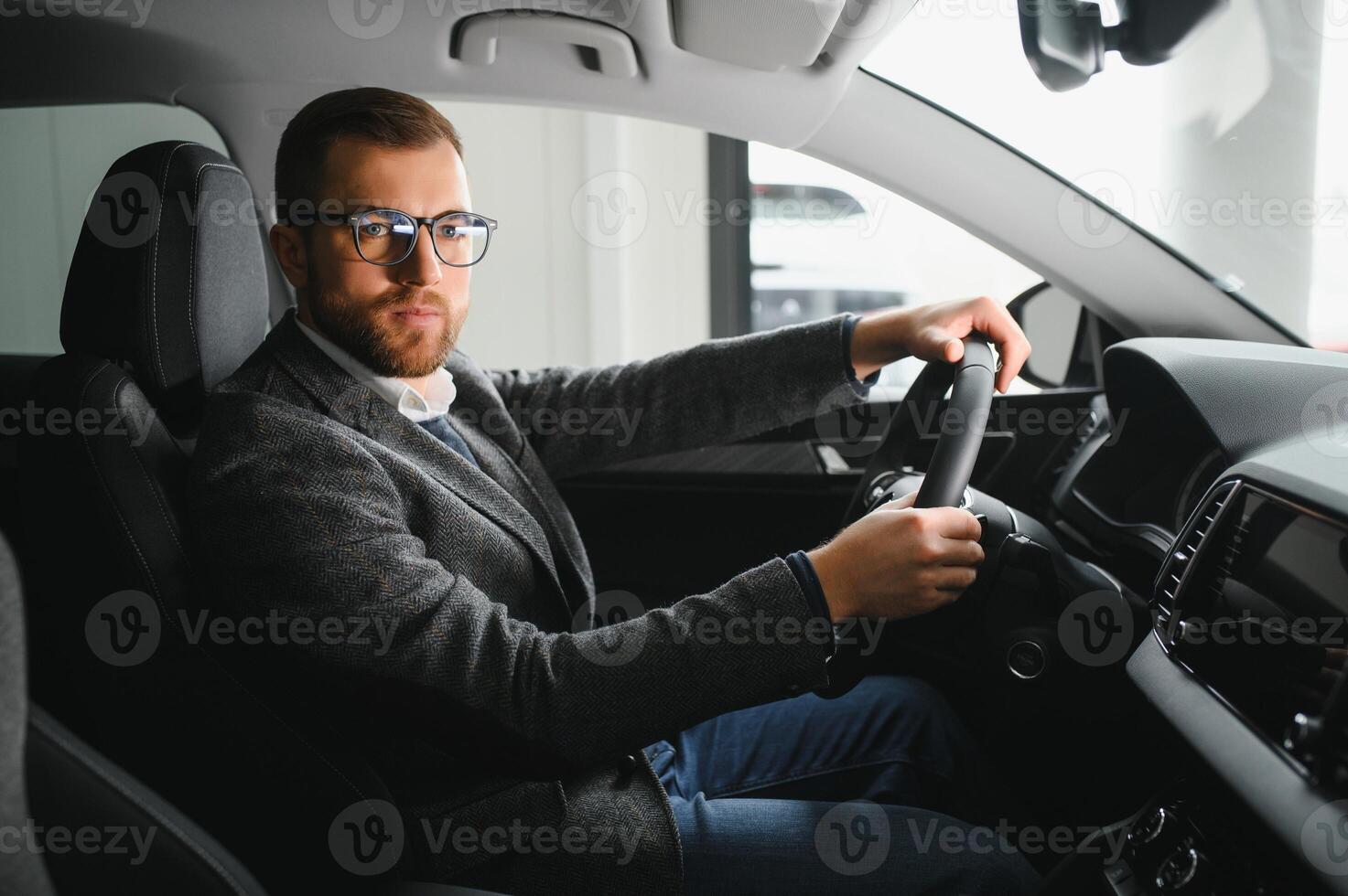 Handsome businessman driving car to airport, going on business side view, copy space. Happy man in stylish suit going to business meeting in the morning, driving his luxury car, shot from cabin. photo