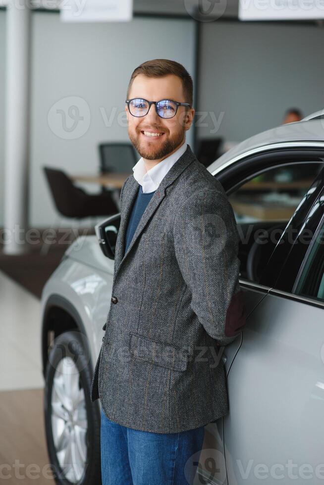 Man adult customer male buyer client wears classic suit white shirt chooses auto wants to buy new automobile touch check car in showroom vehicle salon dealership store motor show indoor photo