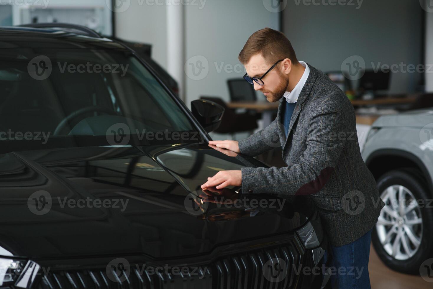 Making his choice. Horizontal portrait of a young man in a suit looking at the car and thinking if he should buy it photo