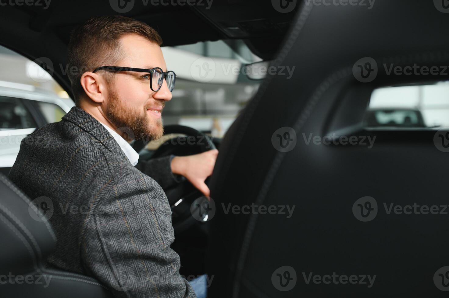 Handsome businessman driving car to airport, going on business side view, copy space. Happy man in stylish suit going to business meeting in the morning, driving his luxury car, shot from cabin. photo