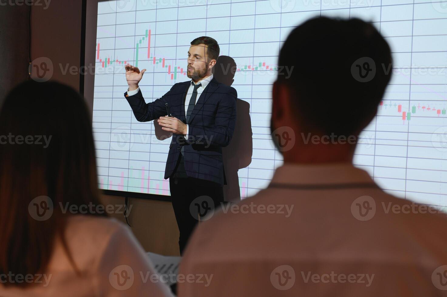 Man is standing near projector and showing graphs and business graphs. photo