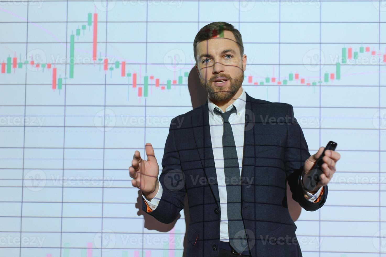 Man is standing near projector and showing graphs and business graphs. photo