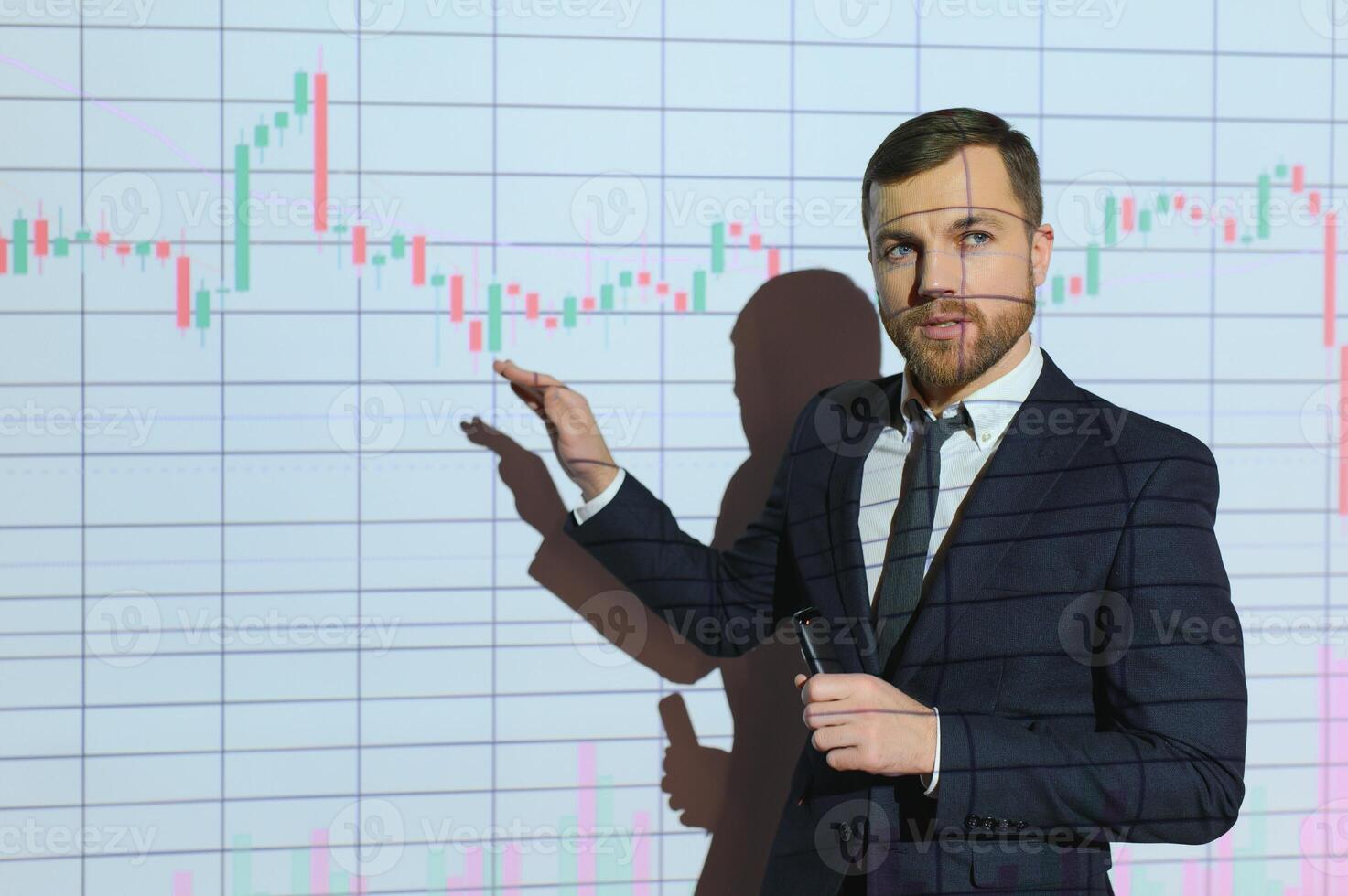Man is standing near projector and showing graphs and business graphs. photo