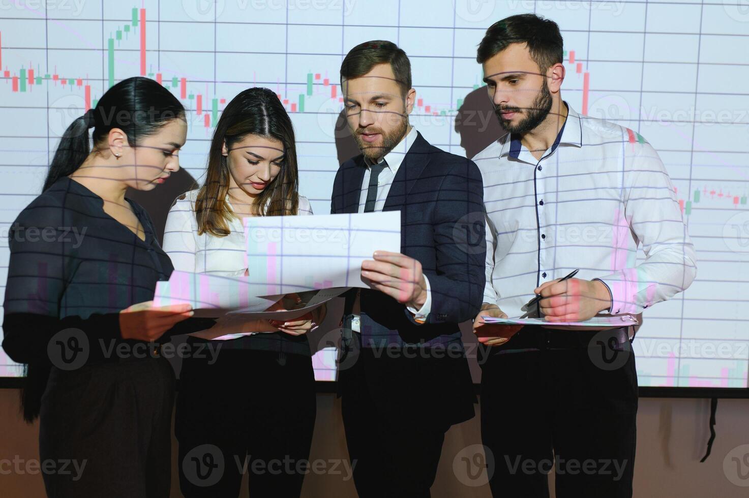 Group of business people working at modern office.Technical price graph, red and blue candlestick chart and stock trading computer screen background. Double exposure. Traders analyzing data photo