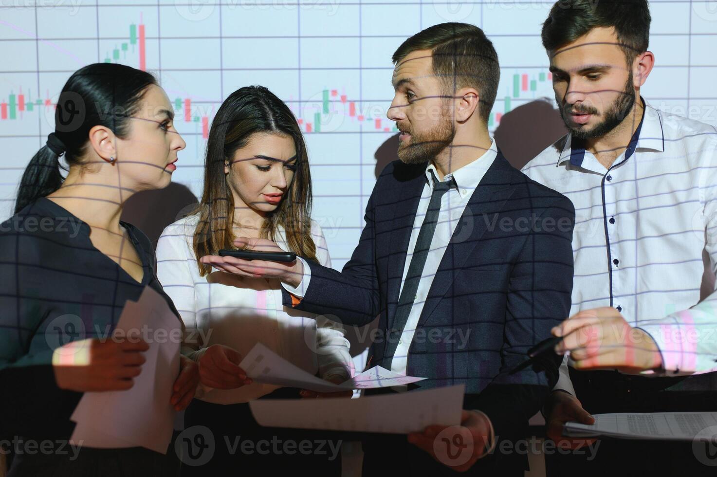 Group of business people working at modern office.Technical price graph, red and blue candlestick chart and stock trading computer screen background. Double exposure. Traders analyzing data photo