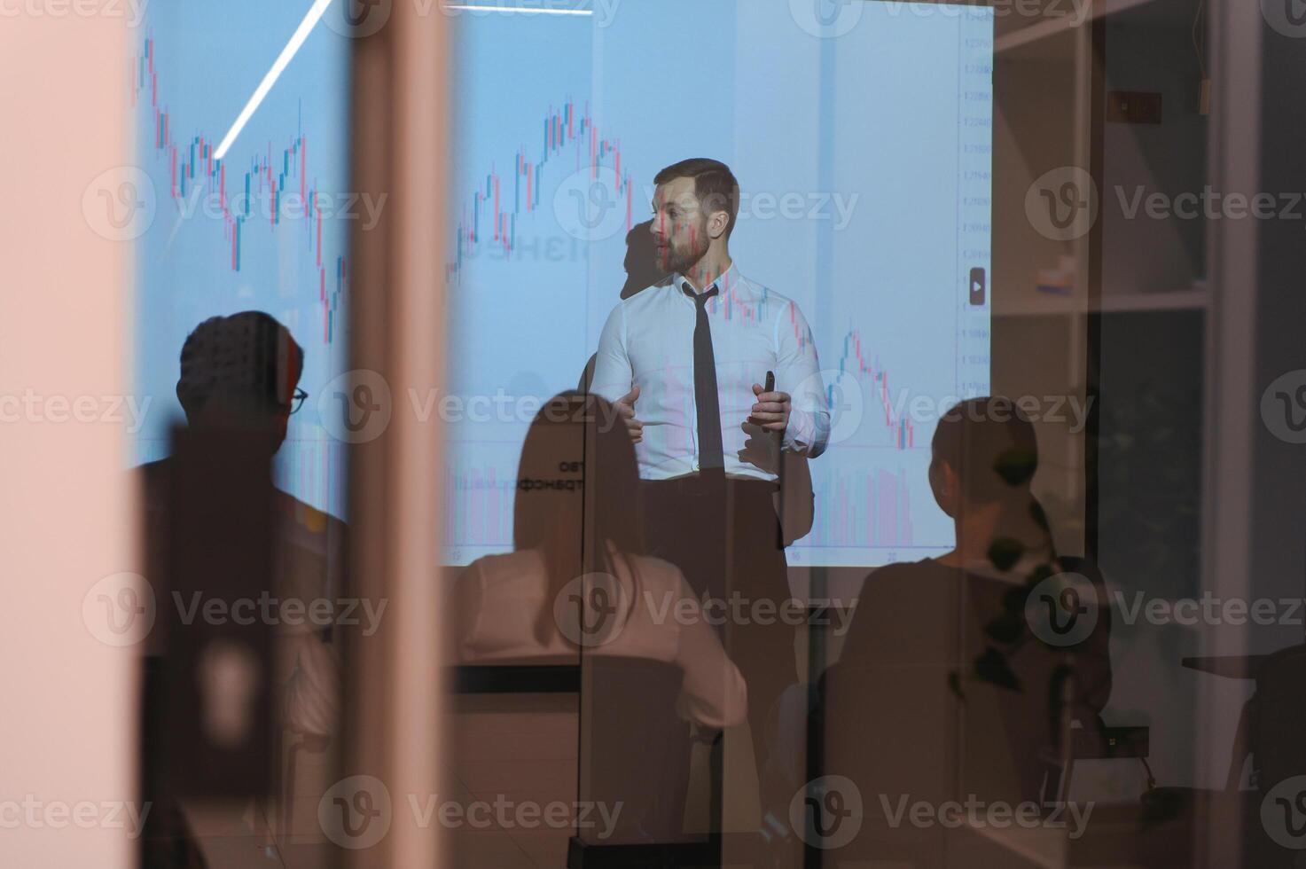 Man is standing near projector and showing graphs and business graphs. photo
