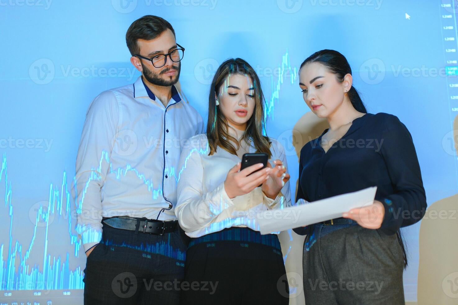 Group of business people working at modern office.Technical price graph, red and blue candlestick chart and stock trading computer screen background. Double exposure. Traders analyzing data photo