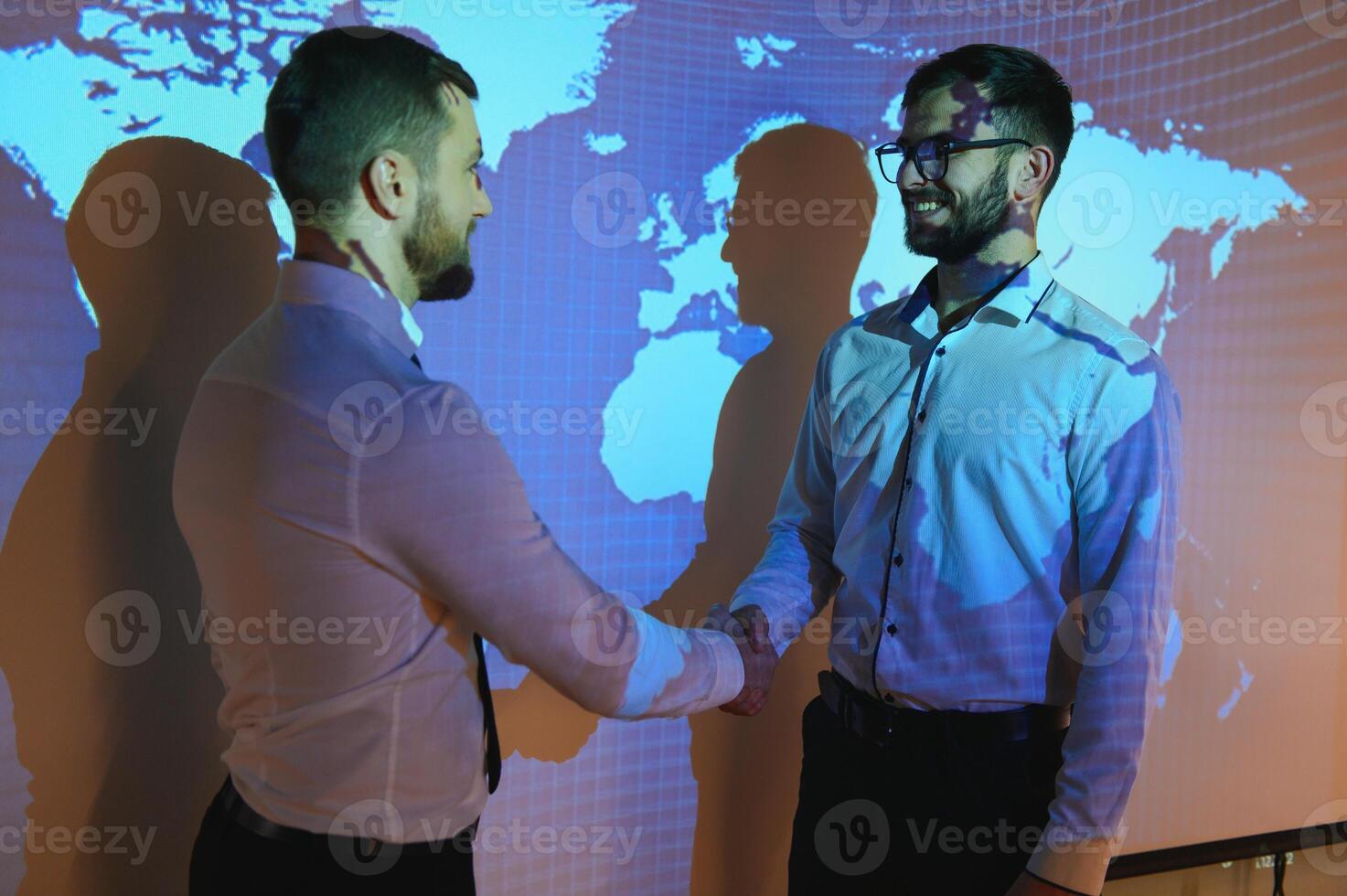 Handshake with map of the world in background. two businessmen on the background of the world map shake hands, the concept of international relations photo