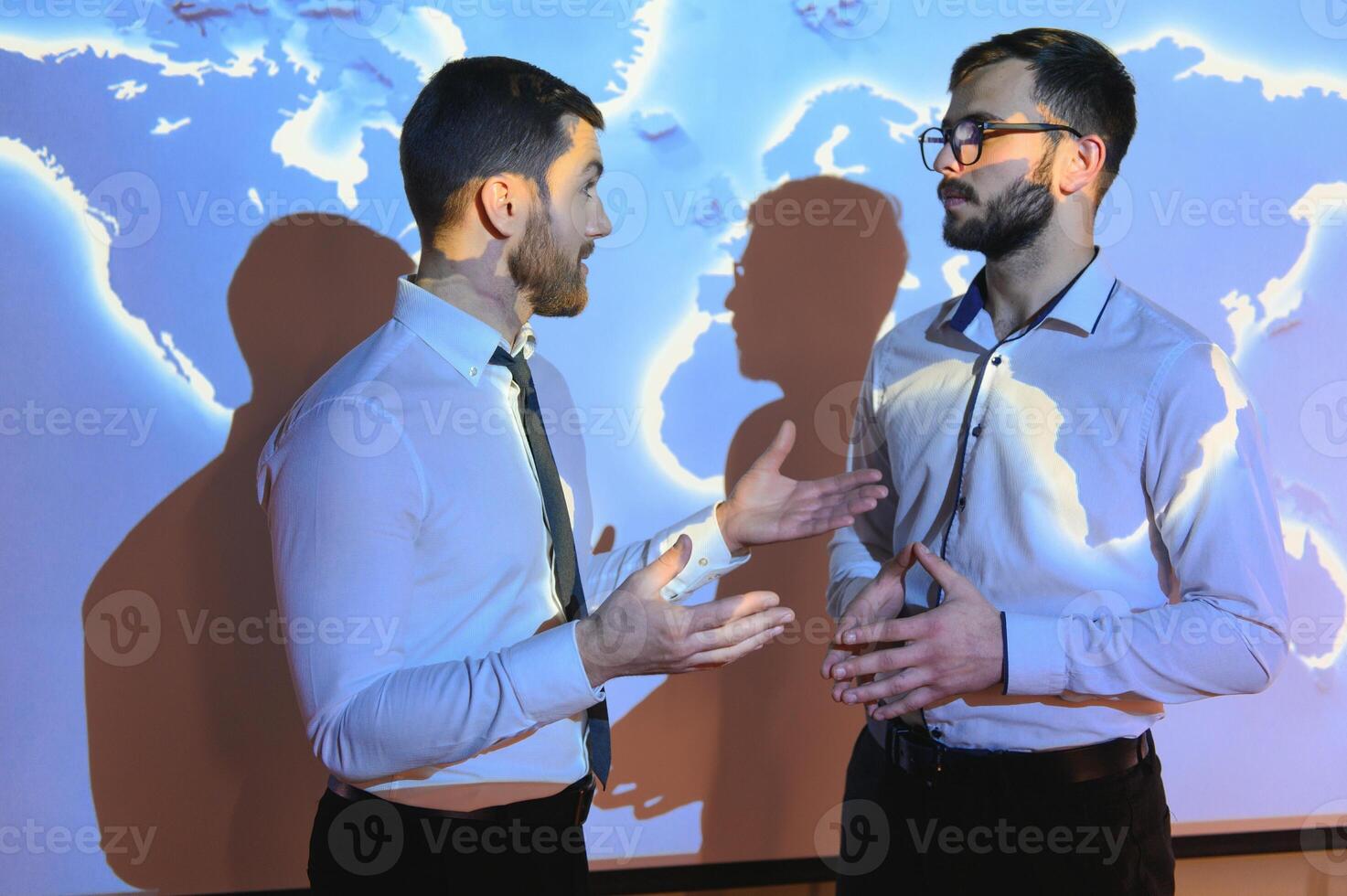 Two Business Colleagues Have Informal Meeting On Stairs Of Office With World Map In Background photo
