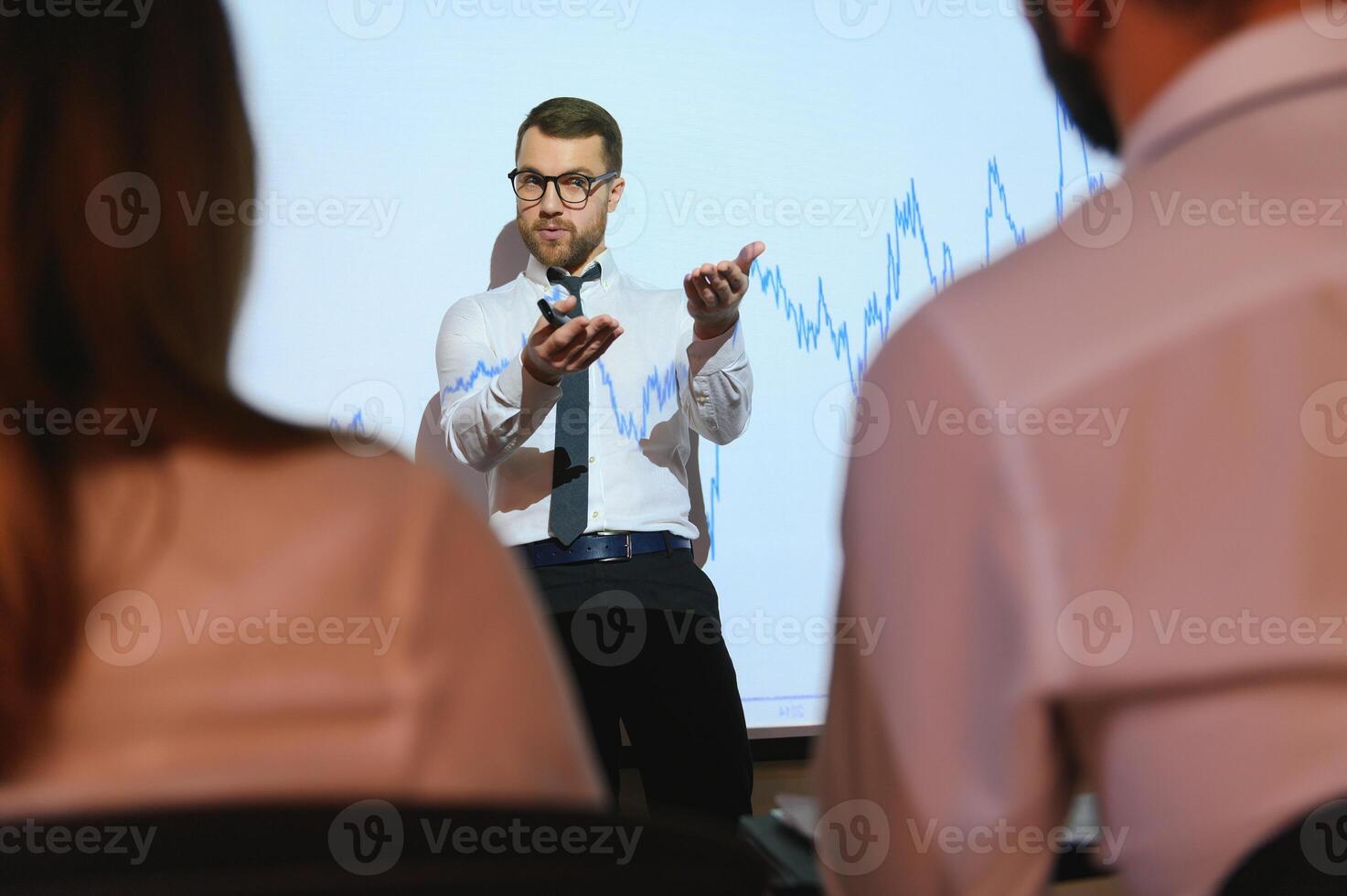 Trading teaching. Male leader talking to employees, showing the plan on the projector in office of stock exchange company. photo