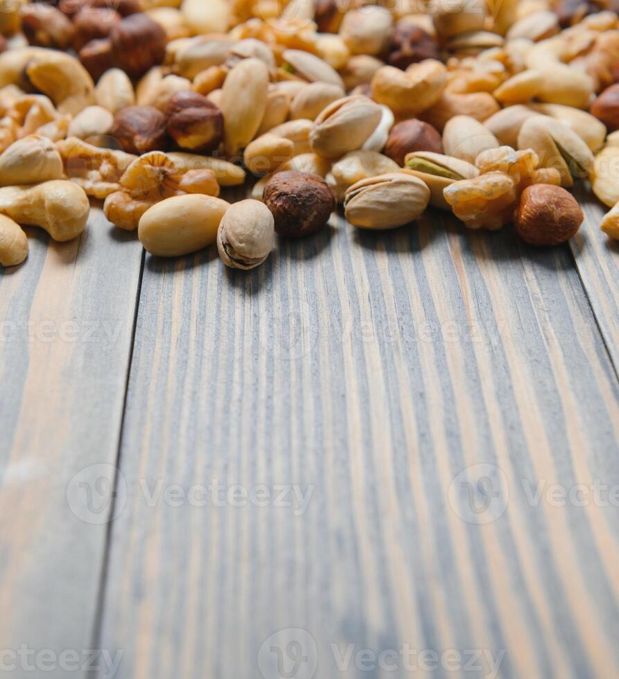 mixed nuts in a bowl on wooden table, top view with copy space. photo