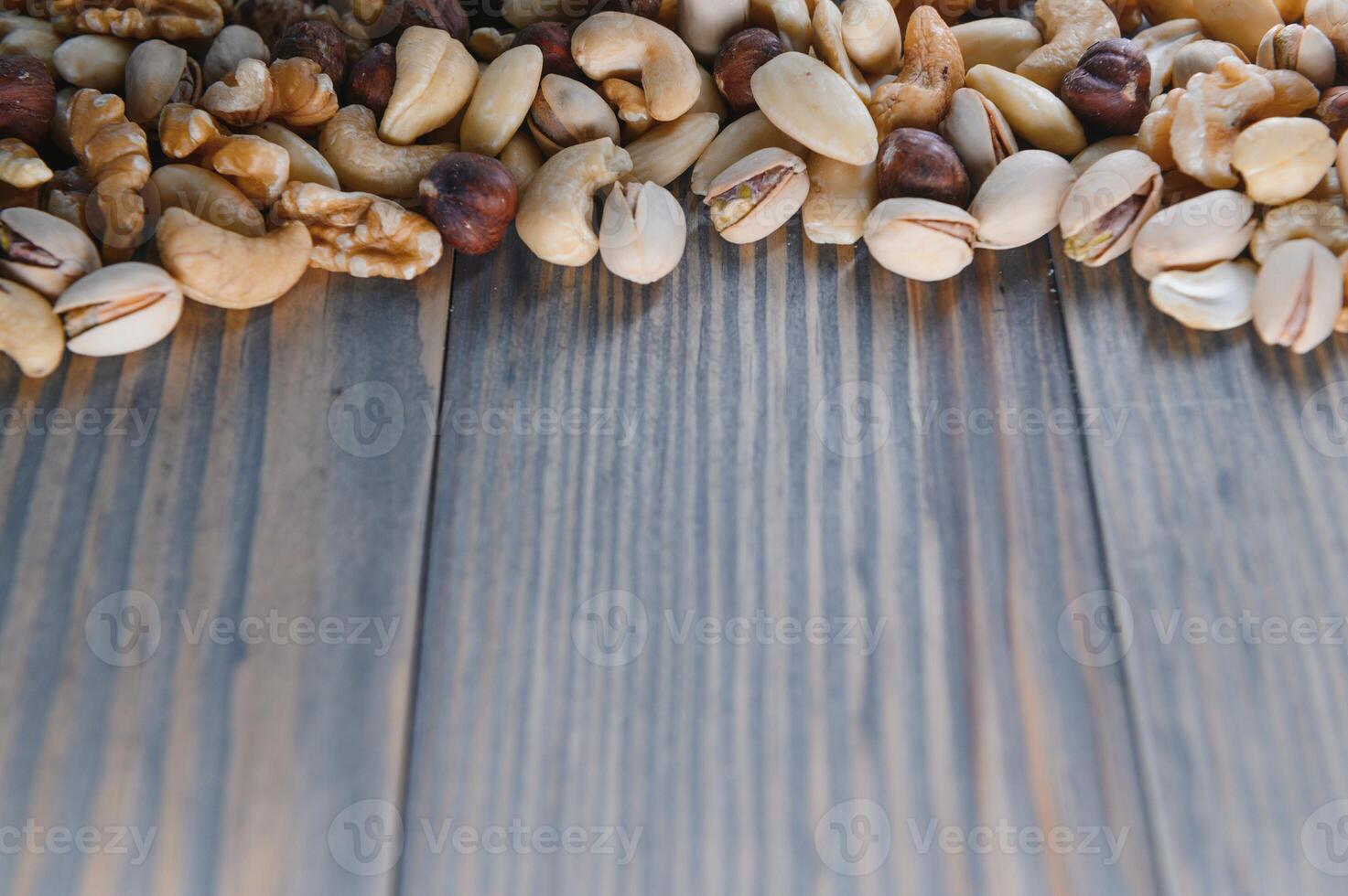 mixed nuts in a bowl on wooden table, top view with copy space. photo